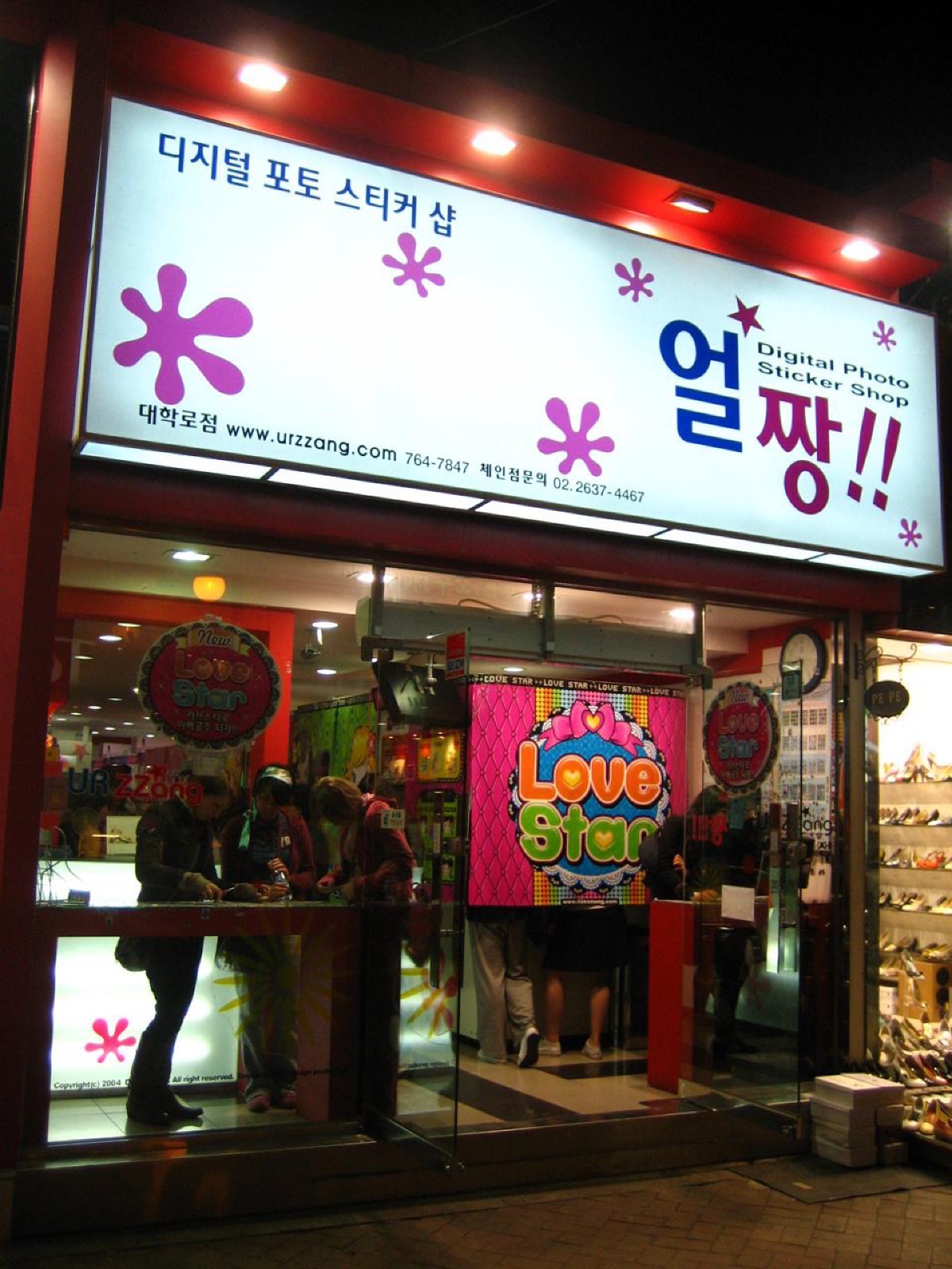 밤에 불 켜진 사진 스티커 가게 간판